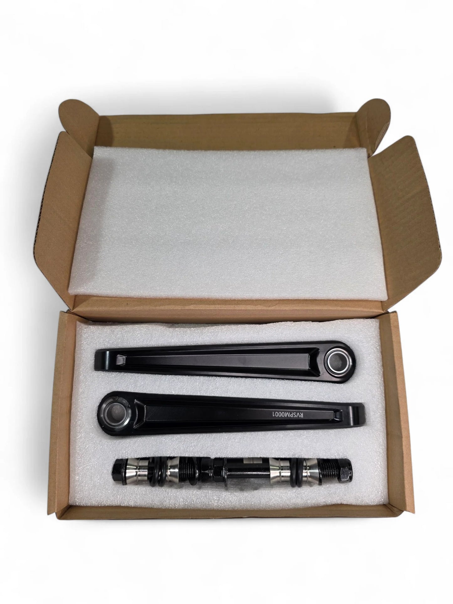 Three black metal components in a cardboard box with styrofoam padding.
