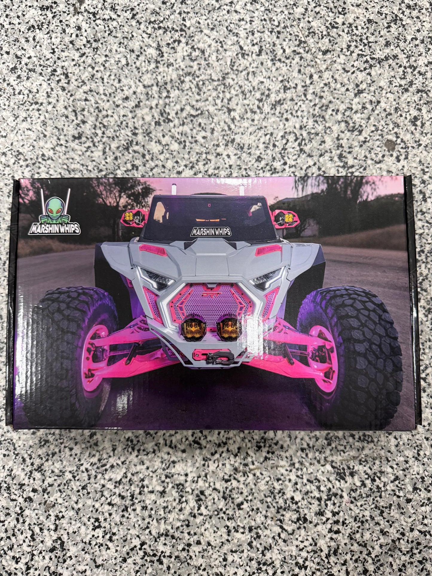 Box with a pink and black off-road vehicle design on a speckled gray surface