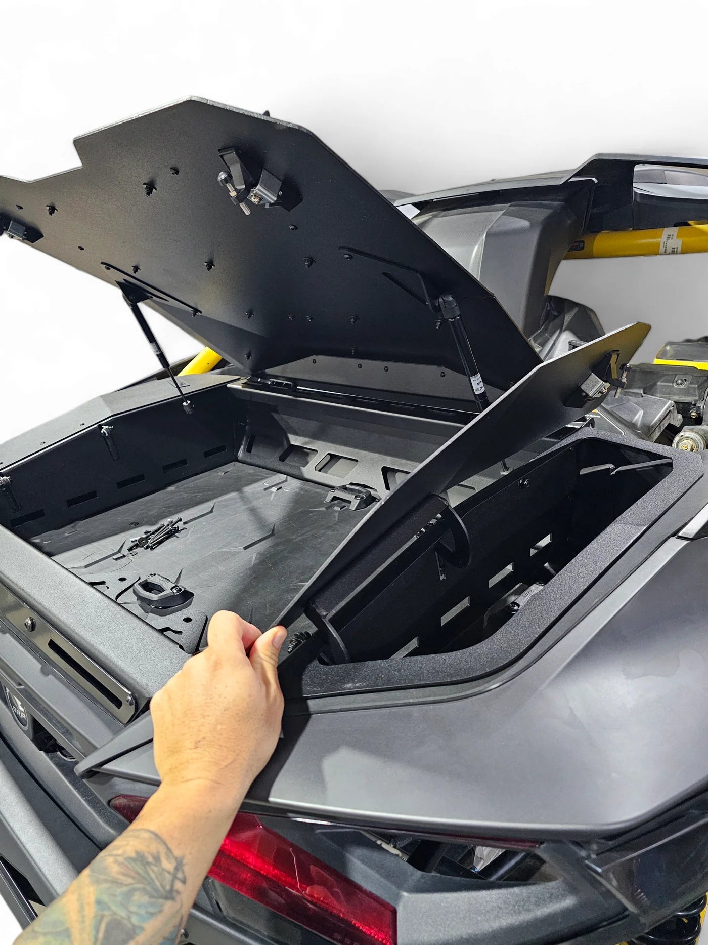 Person opening the trunk of a car with a black protective cover.