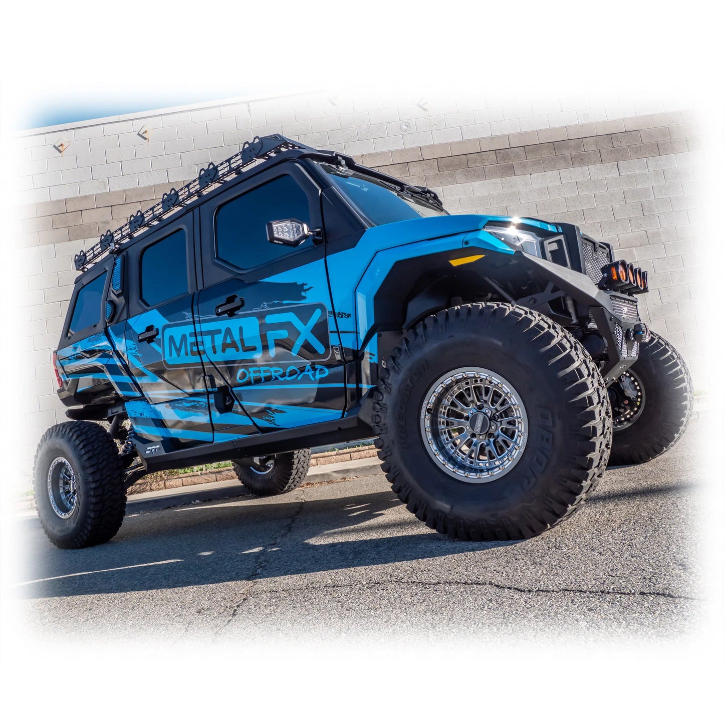 Blue off-road vehicle with large tires and 'Metal RX' branding on a concrete surface.