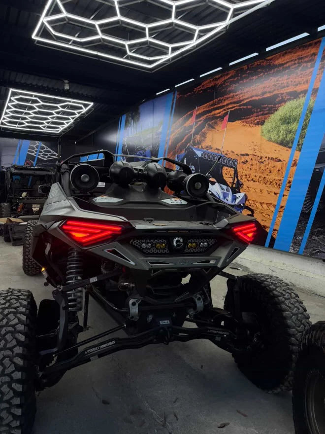 Back view of an off-road vehicle in a showroom with a large mural on the wall.