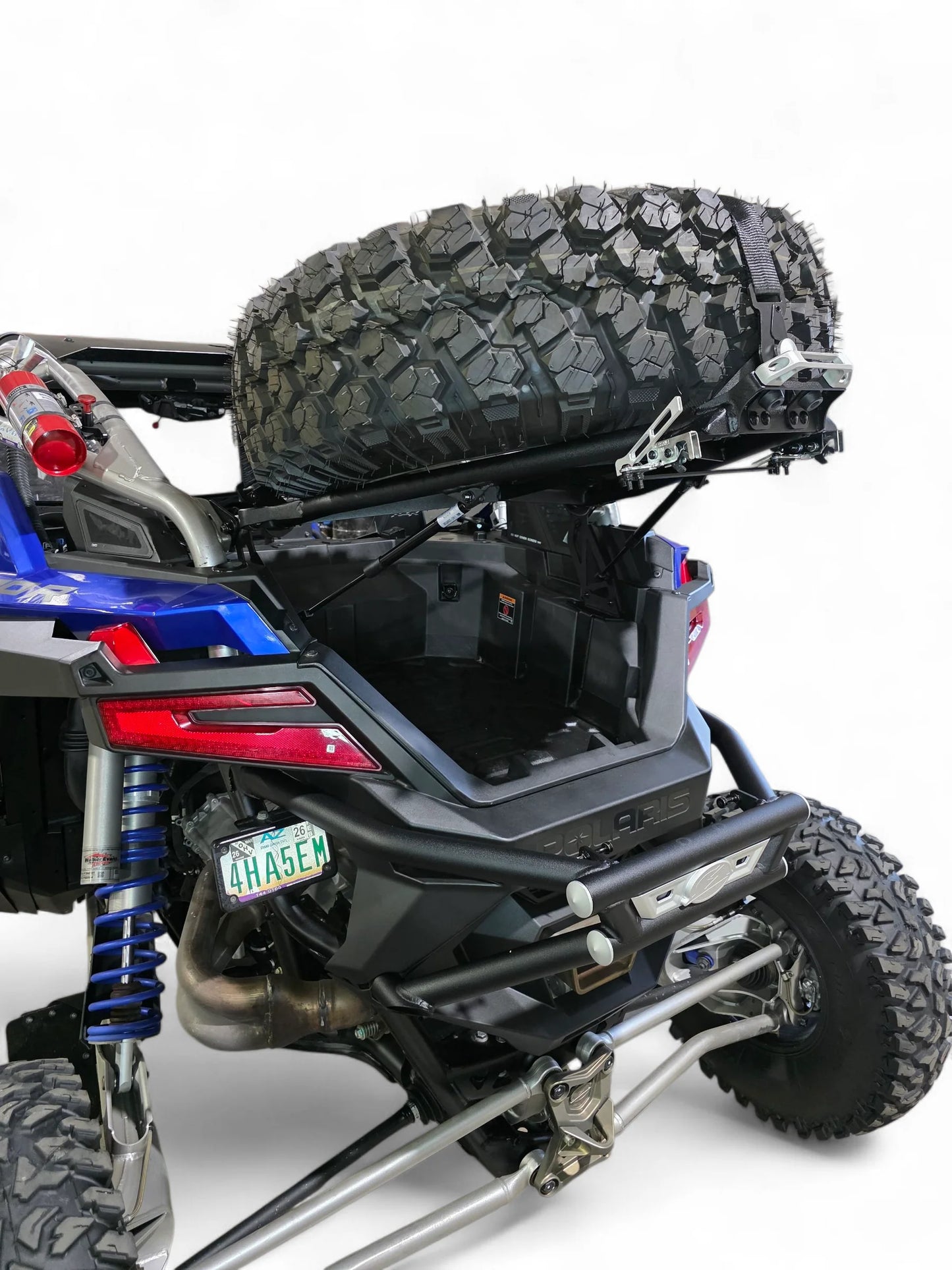 Back view of an off-road vehicle with a tire on a roof rack against a white background