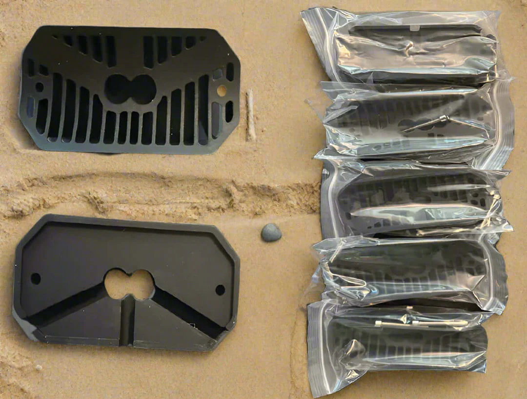 Black metal grates on a cardboard surface with some in clear plastic packaging.