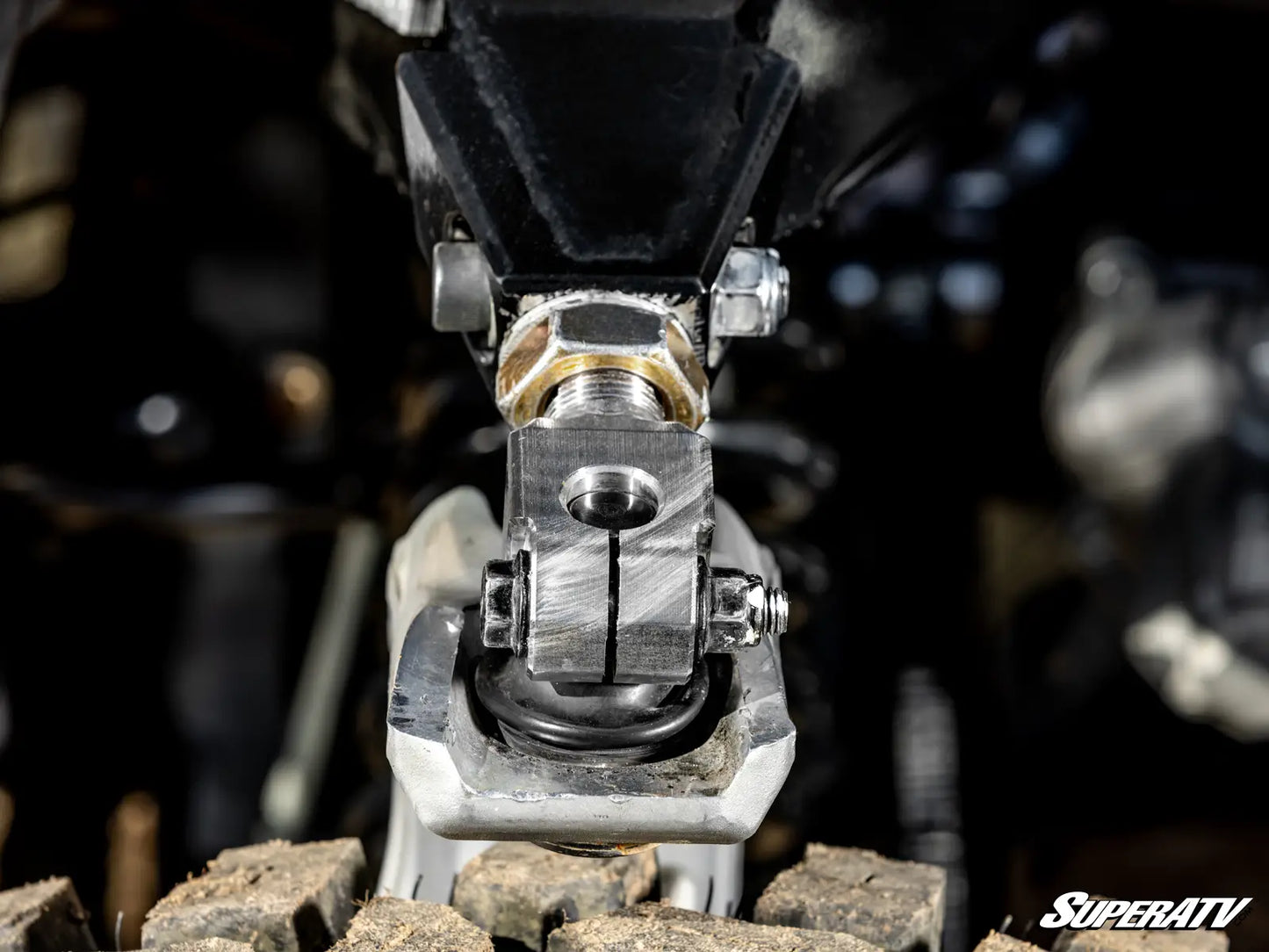 Close-up of a metal lever with bolts on a blurred background, featuring the SuperATV logo.