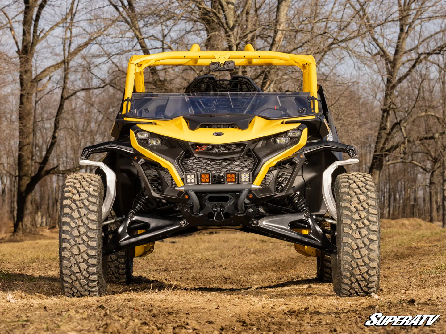 Yellow and black SuperATV vehicle on a dirt path with trees in the background