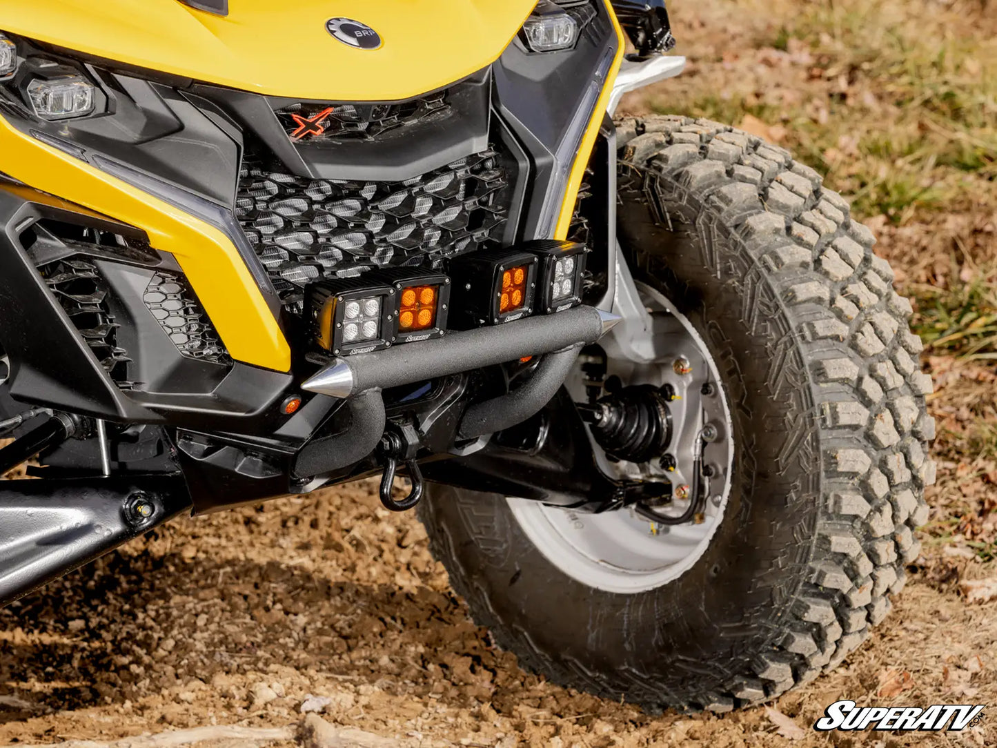 Close-up of a yellow and black ATV with a SuperATV logo on a dirt surface.