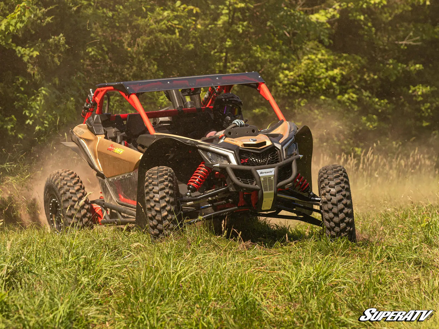 Off-road vehicle driving through a grassy area with trees in the background