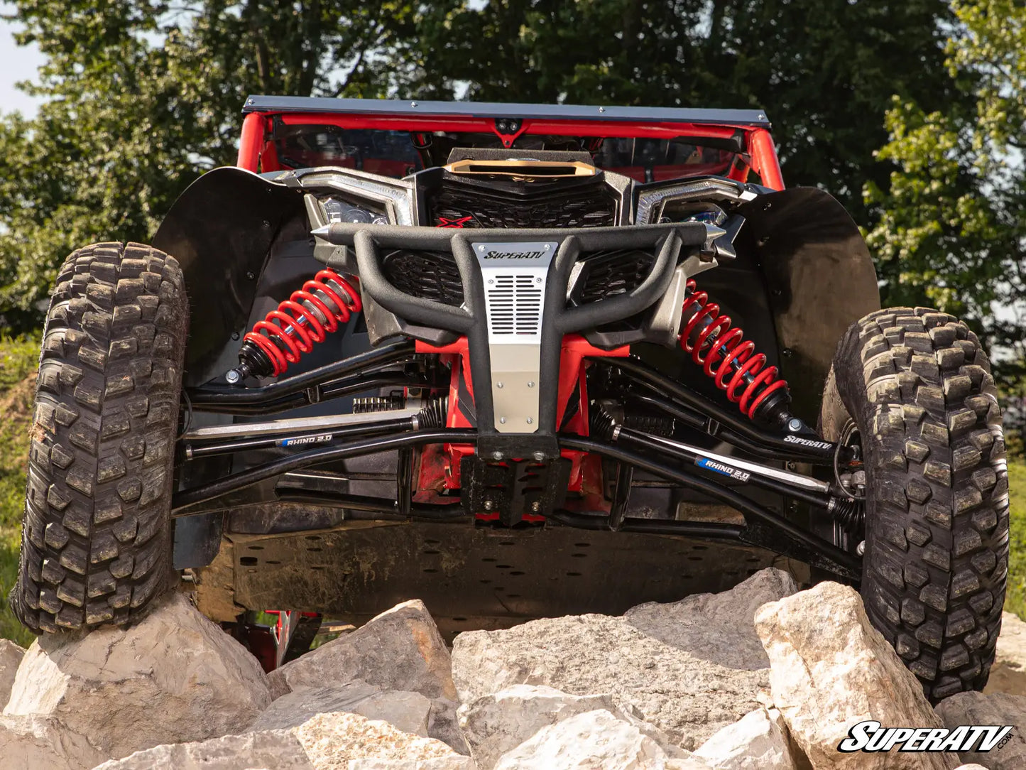 Off-road vehicle with large tires on rocks, featuring SuperATV branding.