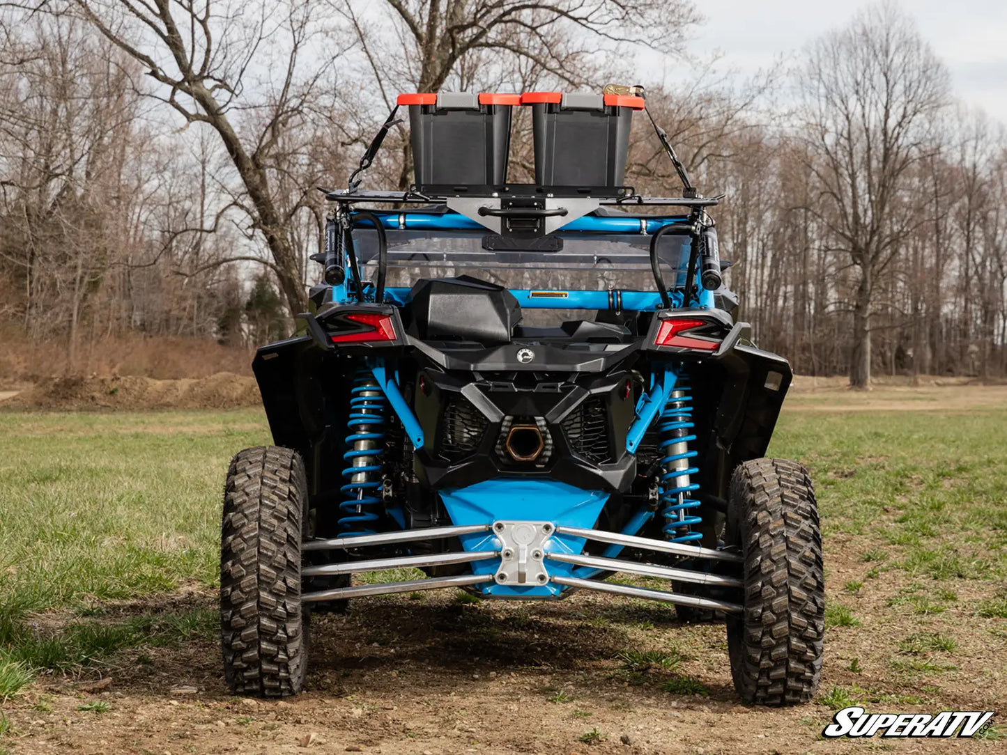 Blue and black off-road vehicle with additional storage on a grassy field.