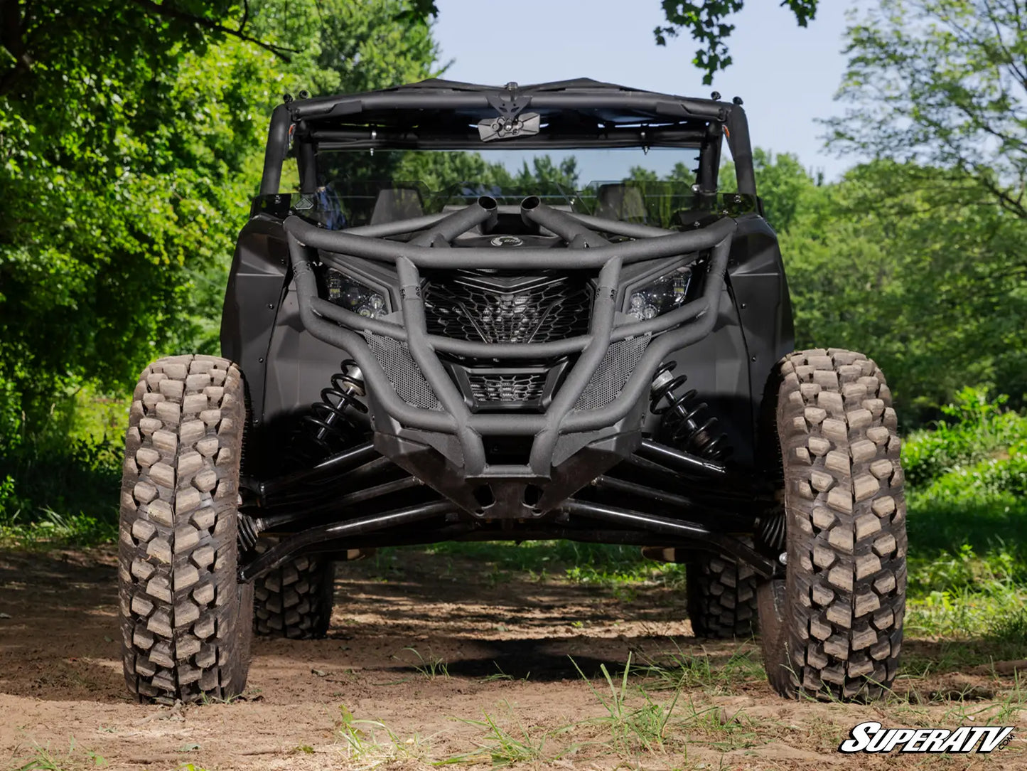 Off-road vehicle in a forested area with 'SuperATV' branding.
