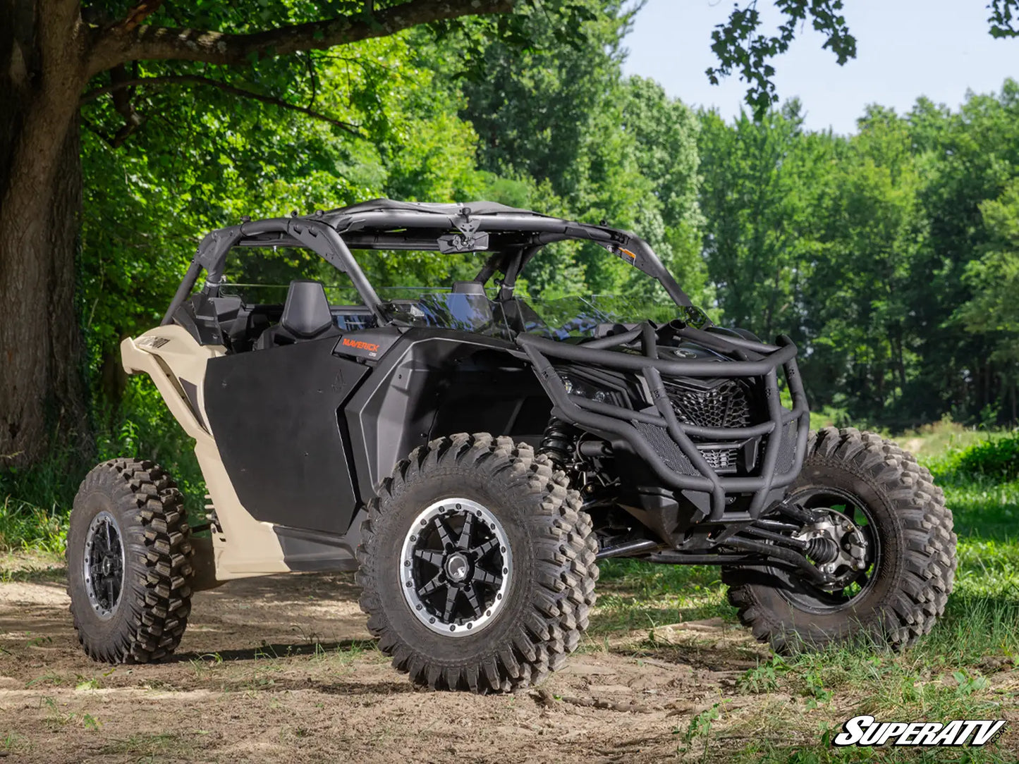 Side view of a black and beige SuperATV UTV in a forest setting