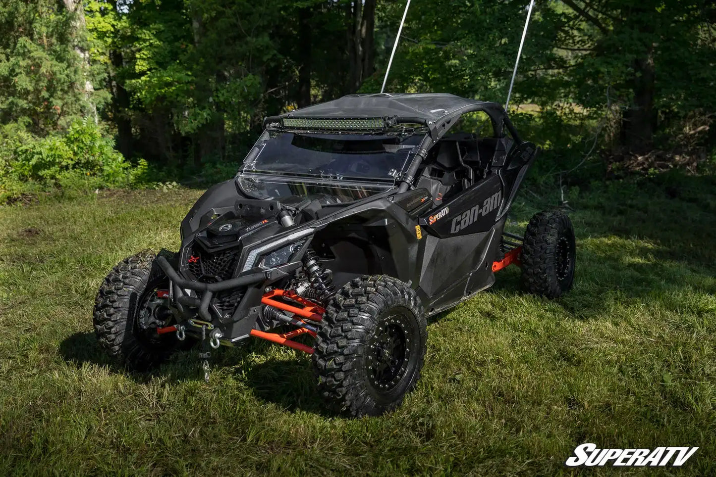 Black off-road vehicle on grass with trees in the background