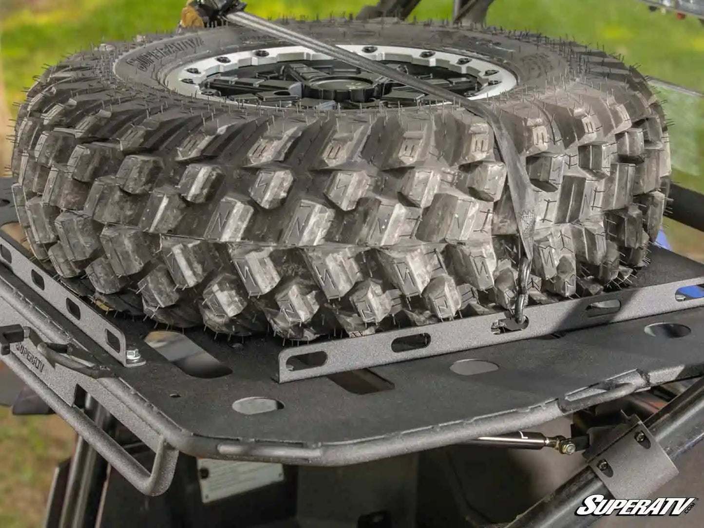 Off-road tire on a SuperATV rack with grassy background
