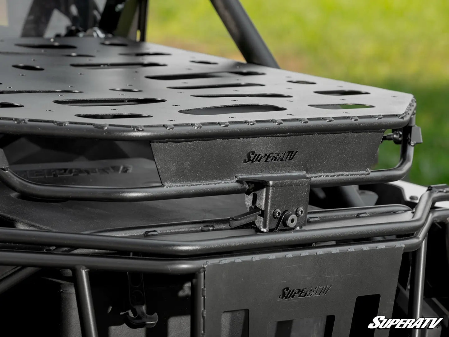 Close-up of a SuperATV roof rack system on a vehicle with a blurred green background.