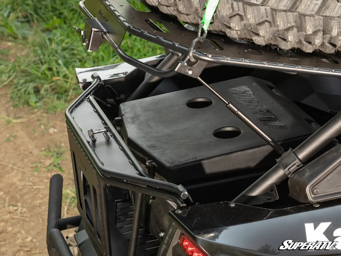 Close-up of a black storage compartment on a vehicle with grass in the background