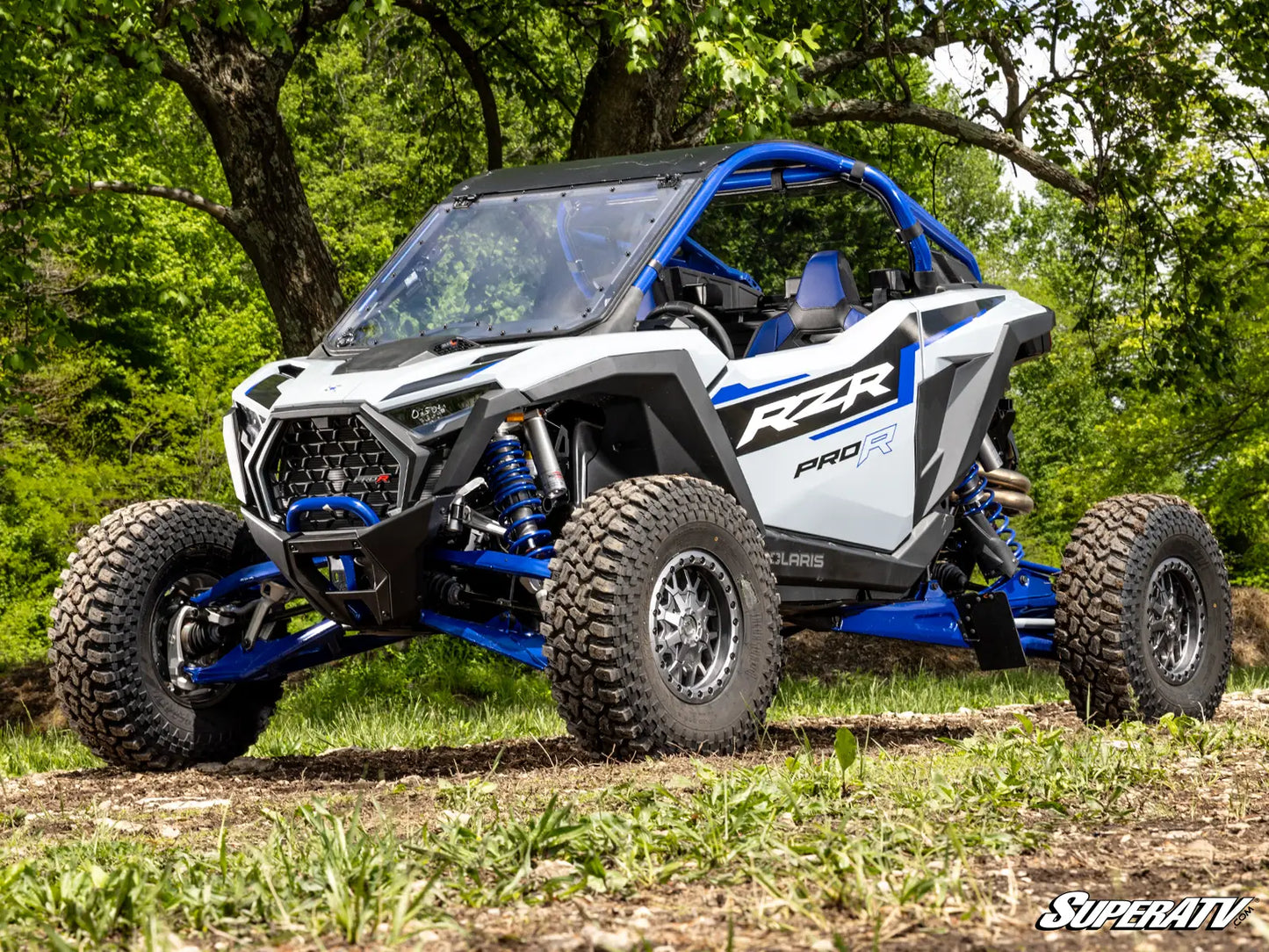 White and blue Polaris RZR Pro R side-by-side vehicle in a forest setting