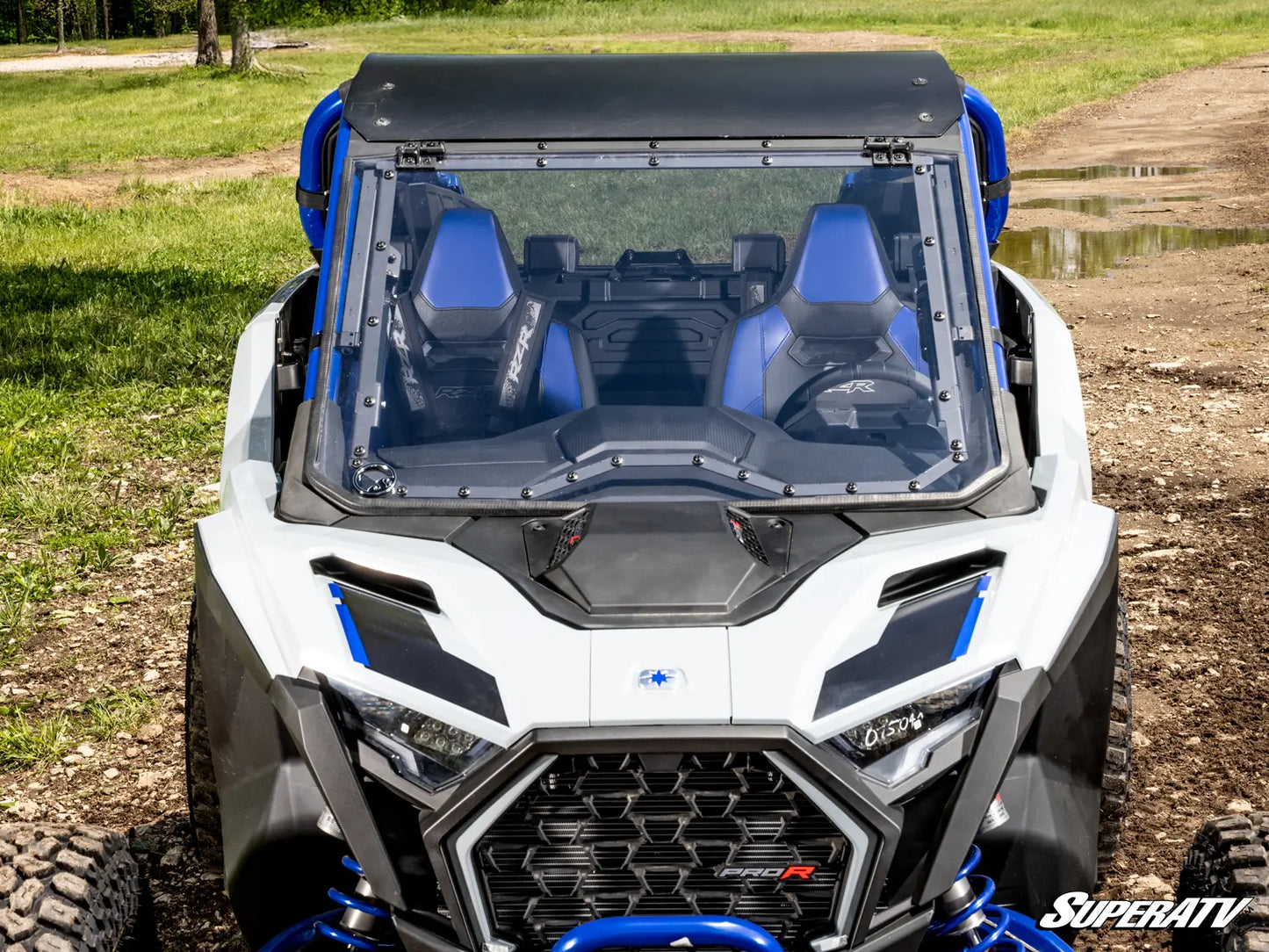 White and blue off-road vehicle with transparent roof on a dirt path