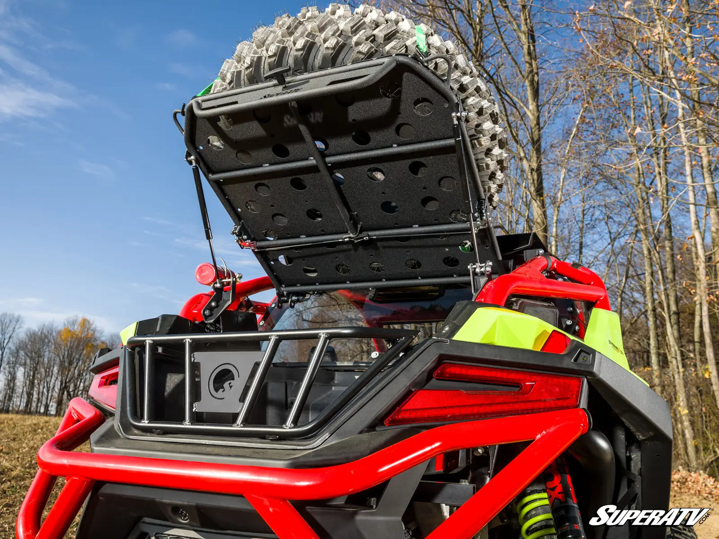 Red ATV with a large tire and storage rack in a forest setting, featuring the SuperATV logo.