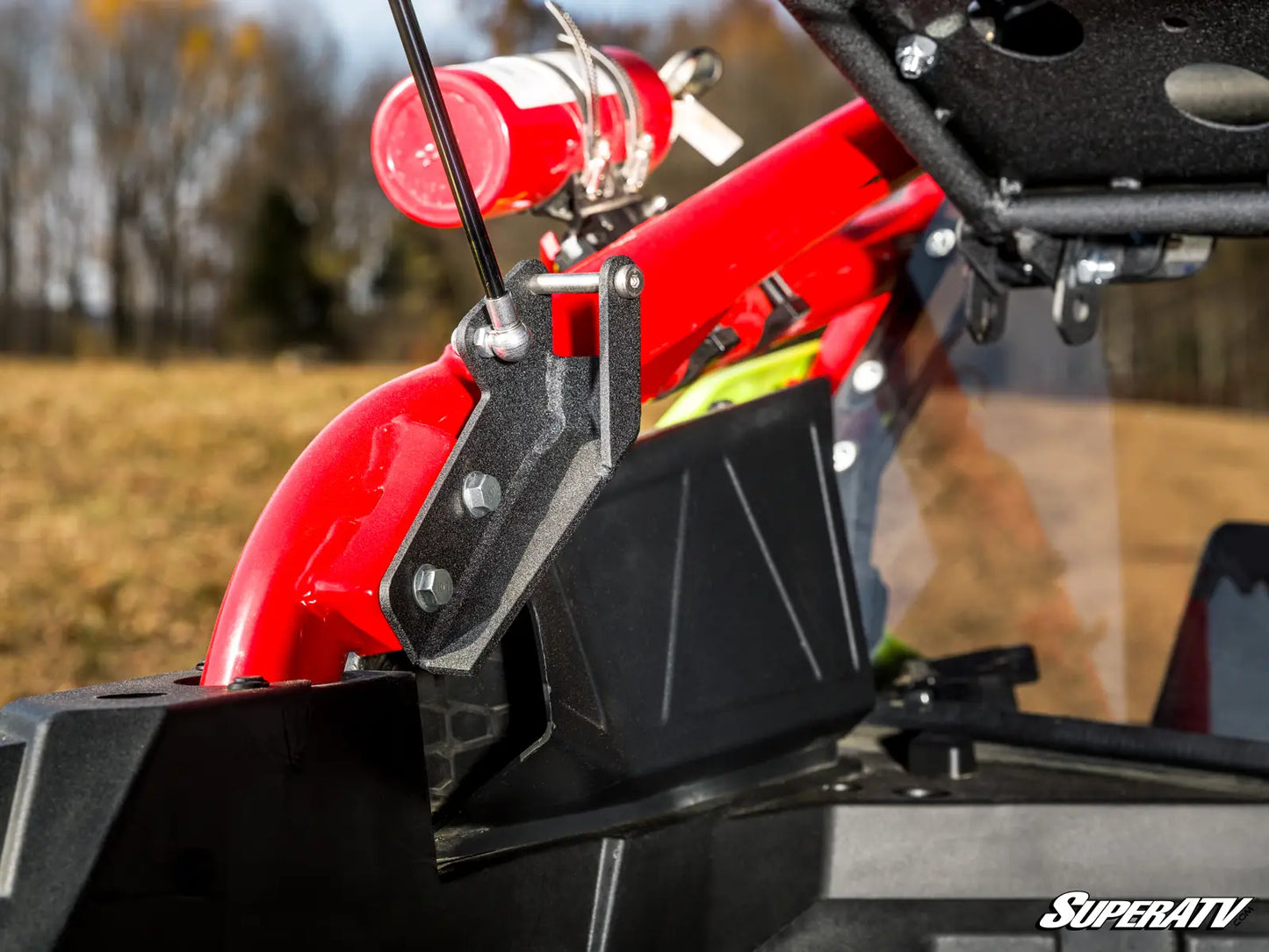 Close-up of a red and black ATV with a SuperATV logo, blurred natural background