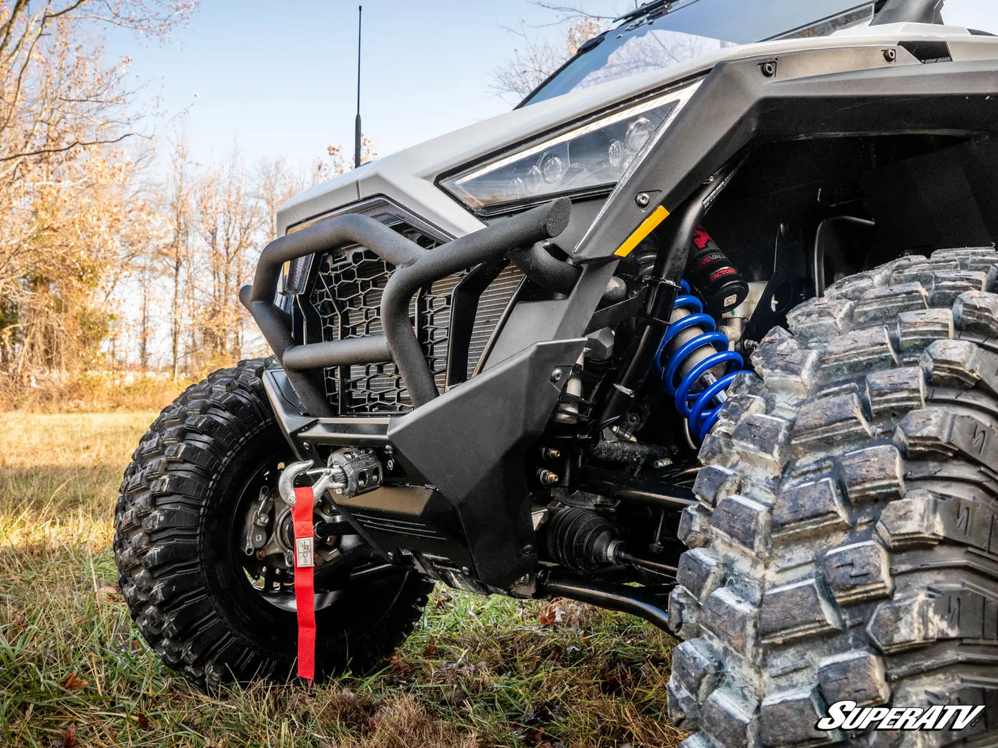 Close-up of an off-road vehicle with large tires and suspension components in a natural setting.