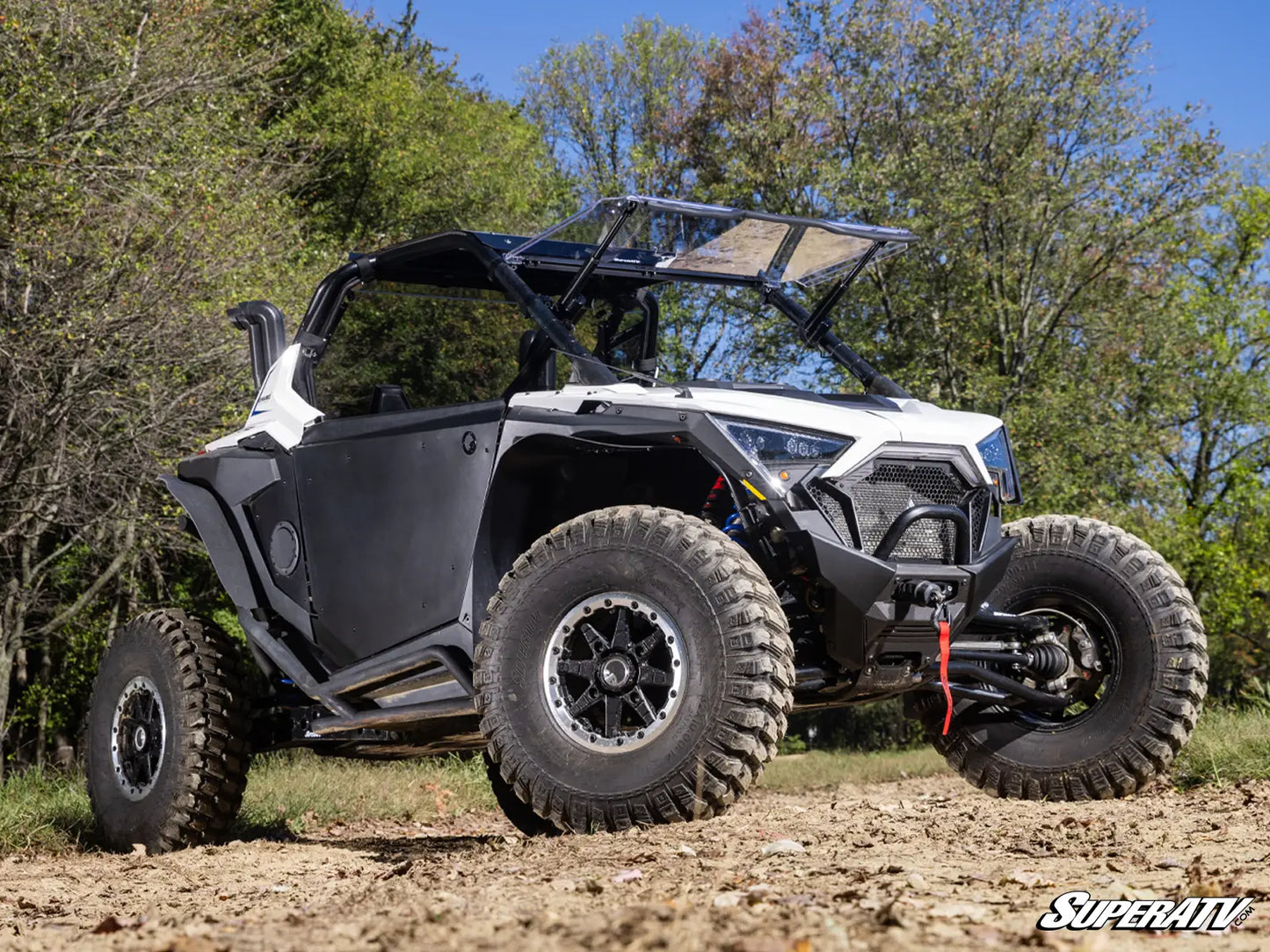 Off-road vehicle on a dirt path with trees in the background