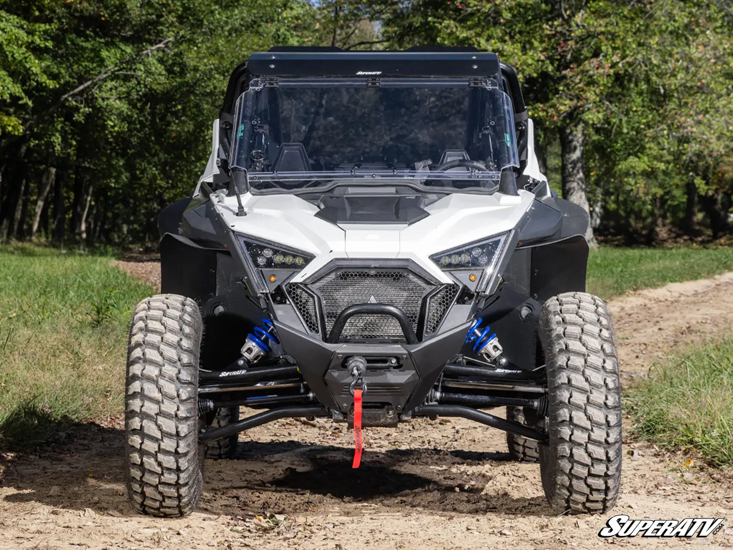 Side-by-side vehicle on a dirt path with trees in the background