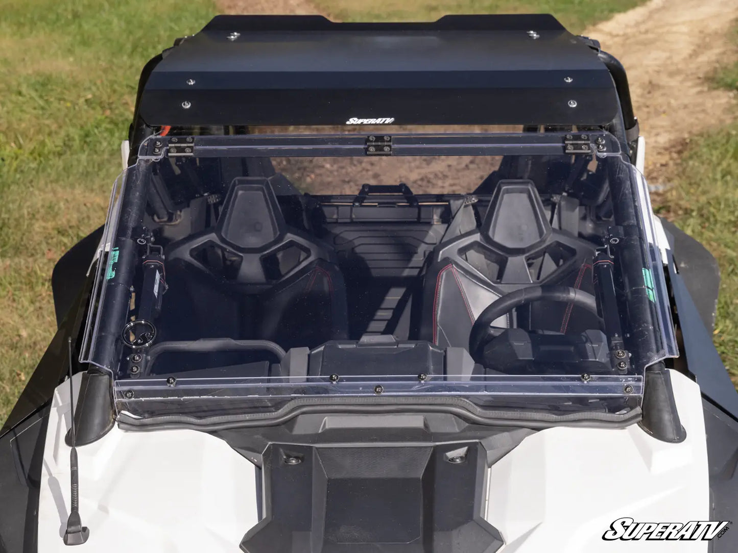 Top view of a black SuperATV roof rack system on a vehicle with grass and dirt in the background.