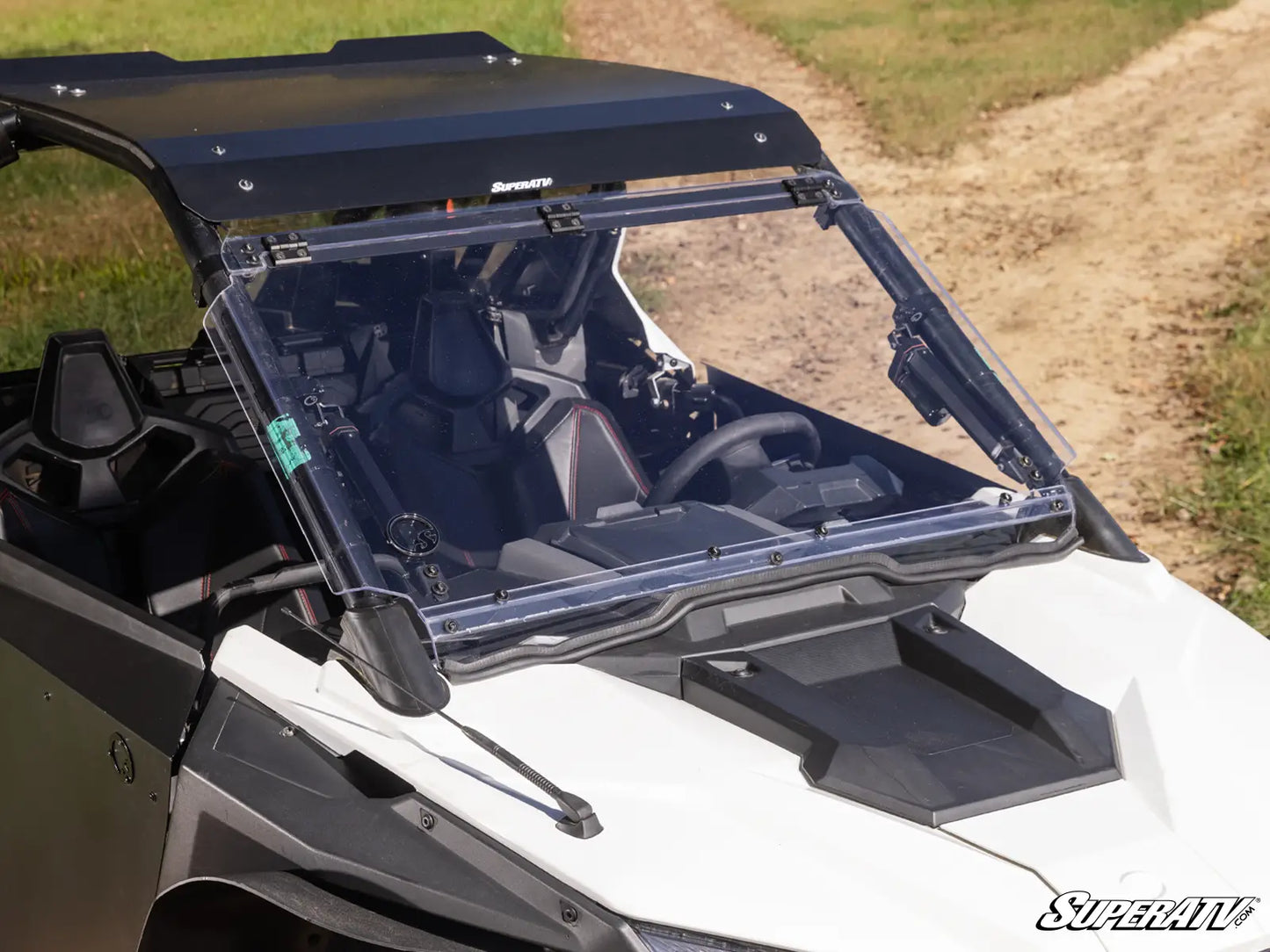 Clear windshield on a white UTV with grass and dirt path in the background
