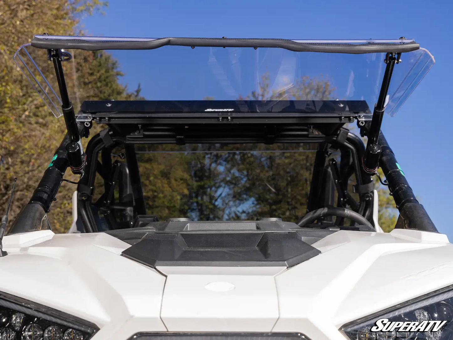 Clear windshield on a white UTV with trees and blue sky in the background