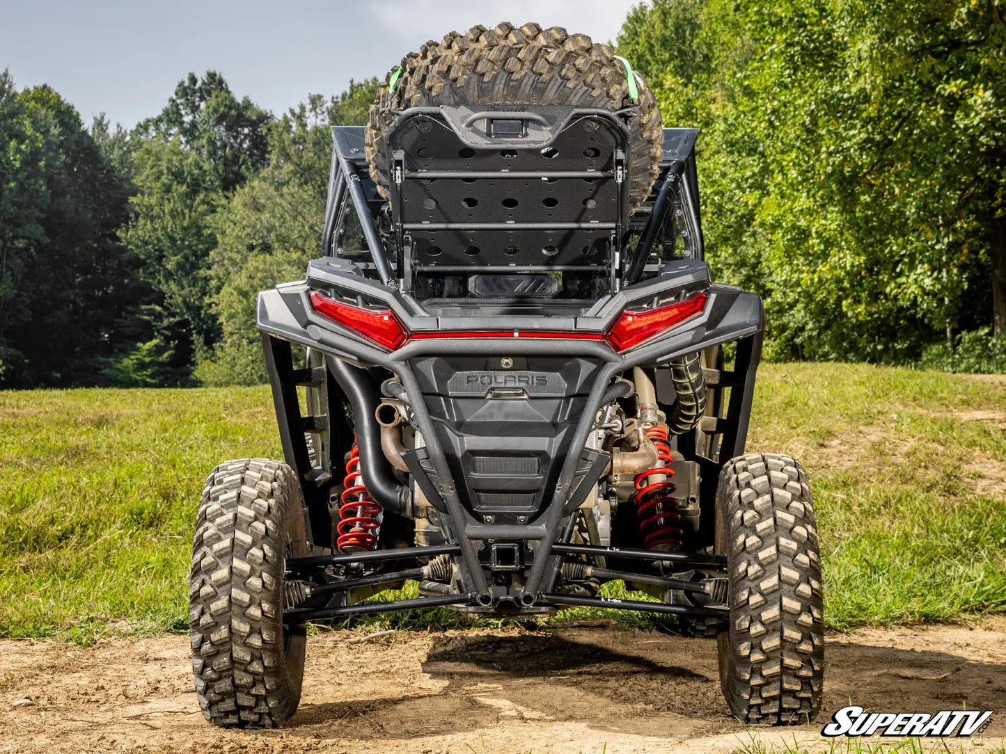 Back view of a SuperATV vehicle in a natural setting with trees and grass.