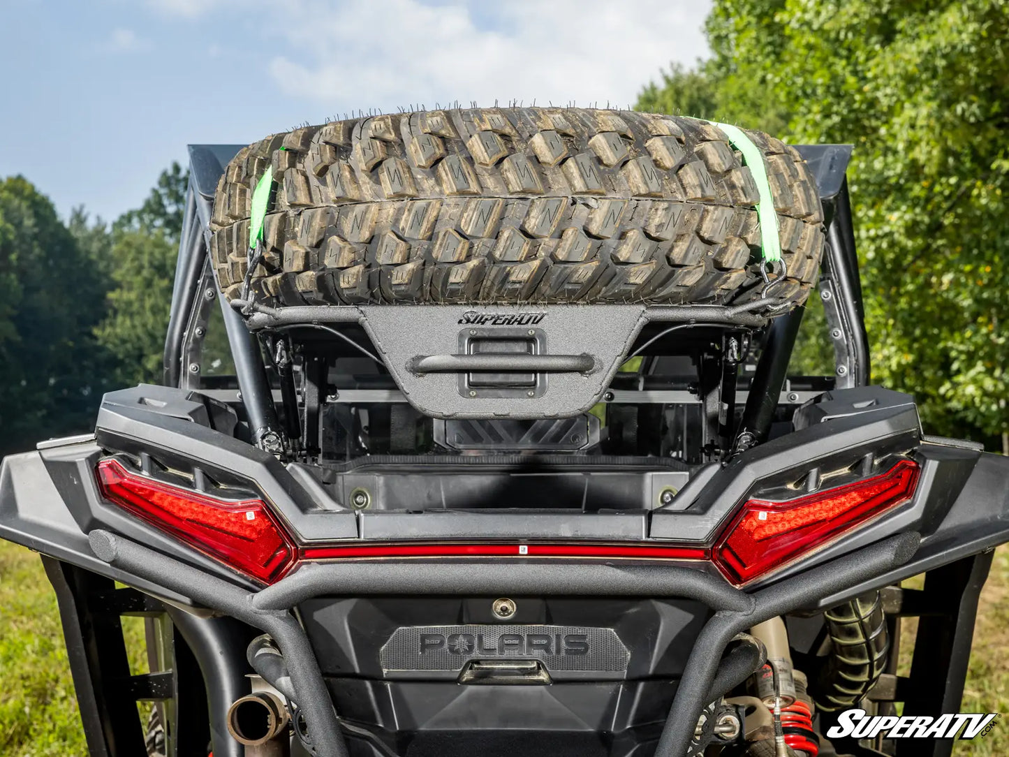Polaris vehicle with a spare tire mounted on the back, surrounded by greenery.