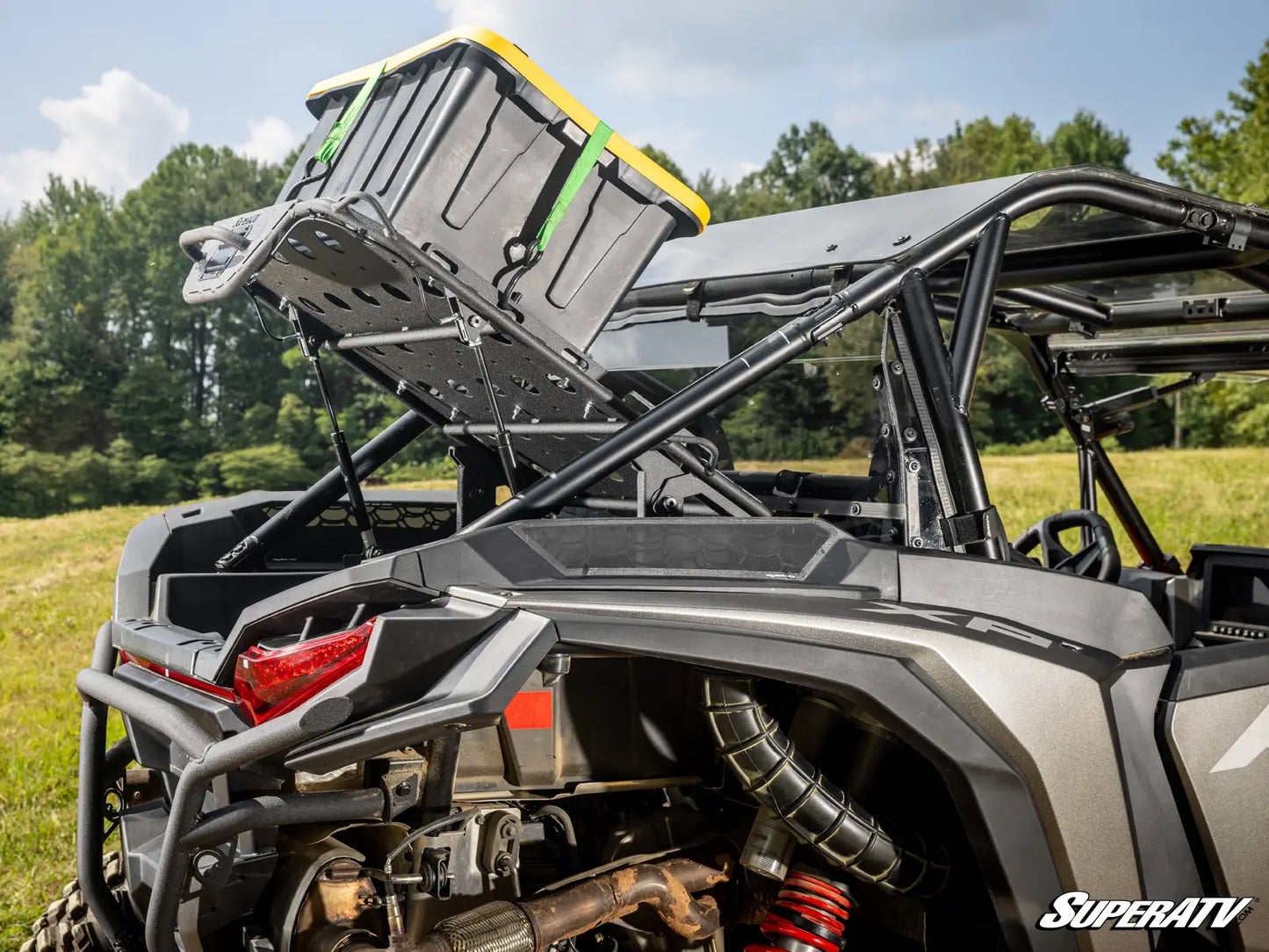 Side view of a SuperATV vehicle with storage rack and equipment on a grassy field.