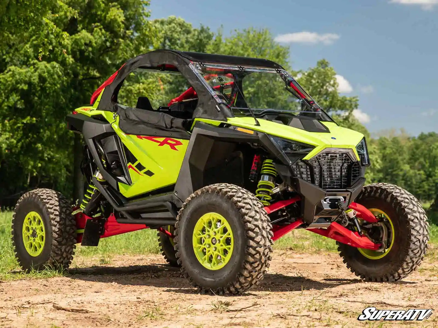 Yellow and black off-road vehicle on a dirt path with trees in the background
