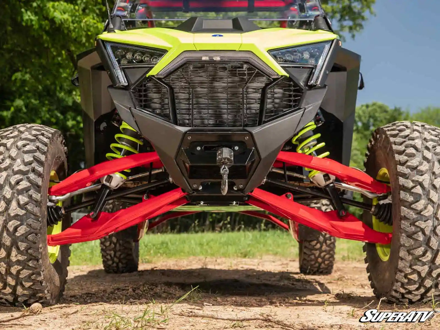 Yellow and red off-road vehicle with large tires on a dirt path.
