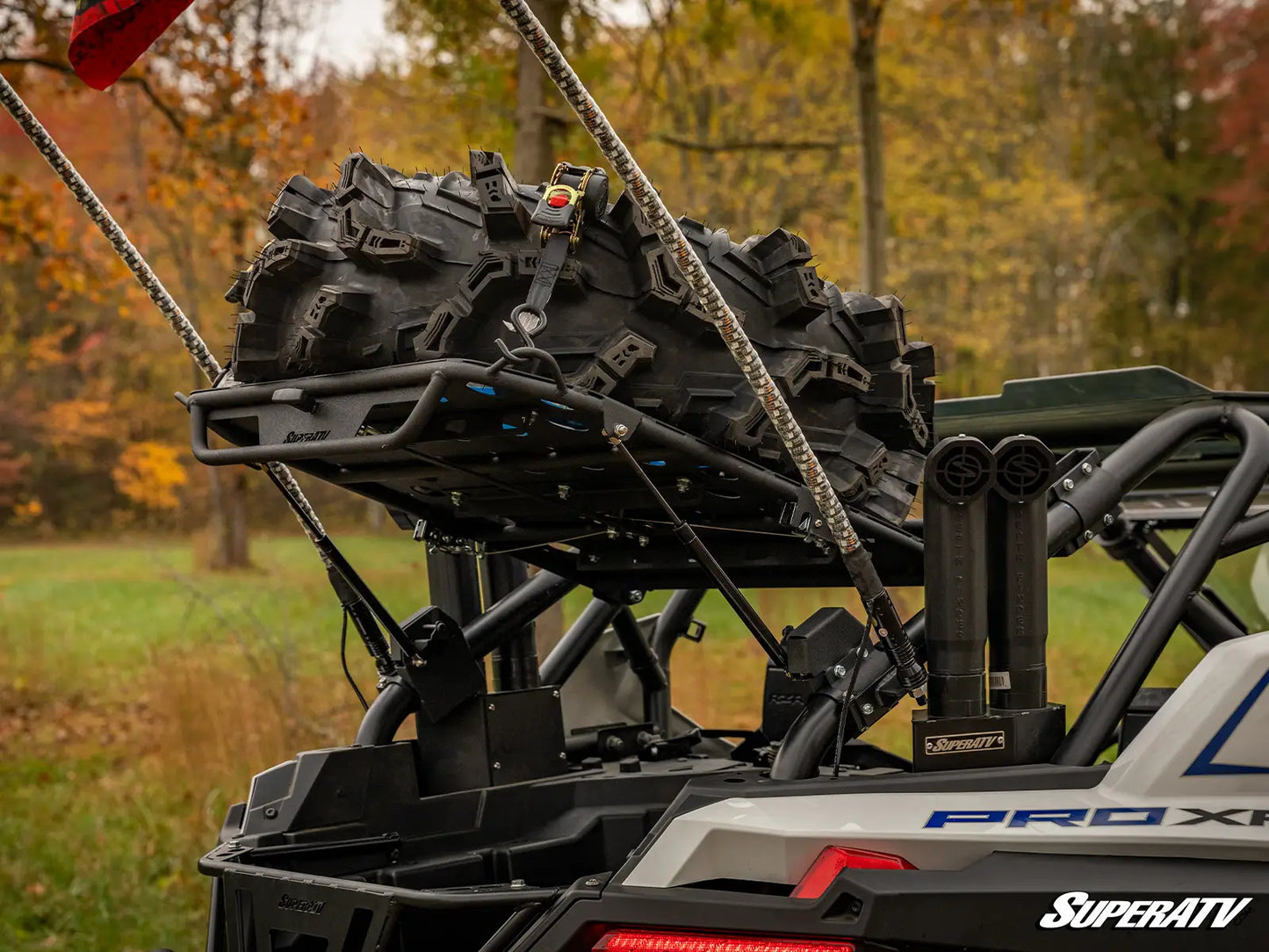 ATV with tire carrier and large off-road tire in a forest setting