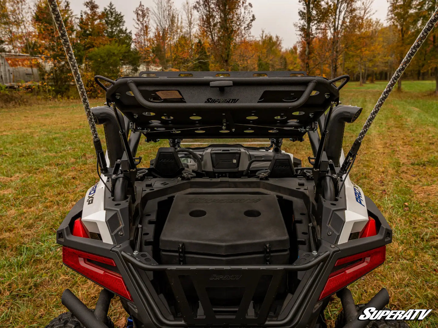 Back view of a SuperATV vehicle with open cargo area on grassy field