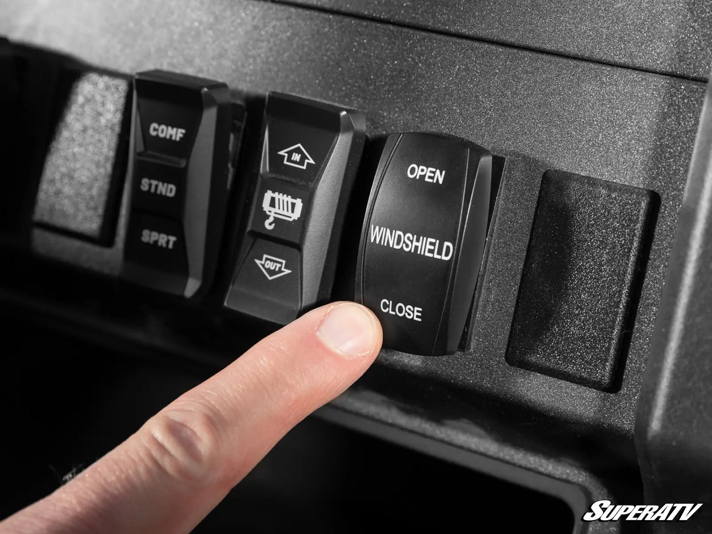 Close-up of a finger pressing a 'Windshield Close' switch on a SuperATV control panel.