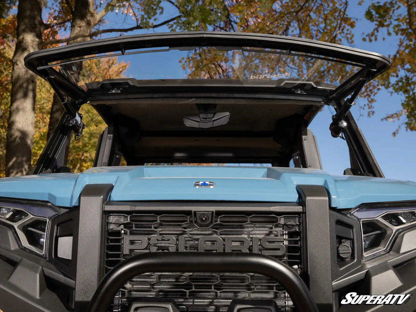 Front view of a blue Polaris vehicle with an open canopy, set against a natural background.