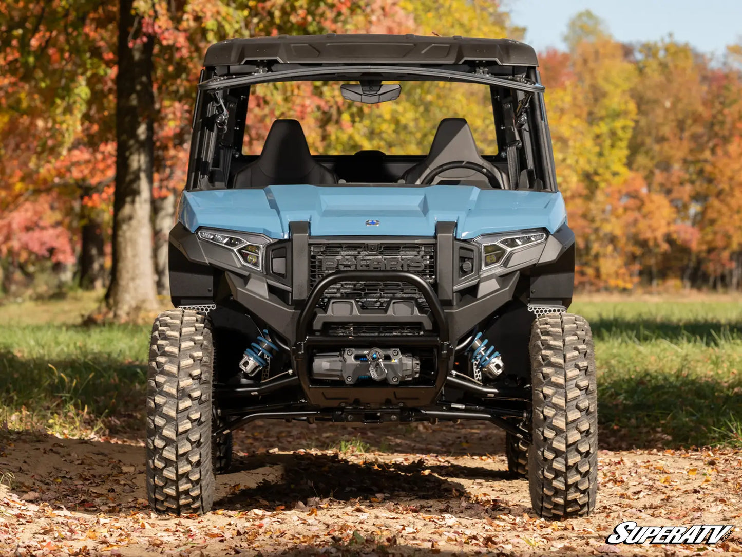 Blue and black UTV in a forest with autumn foliage