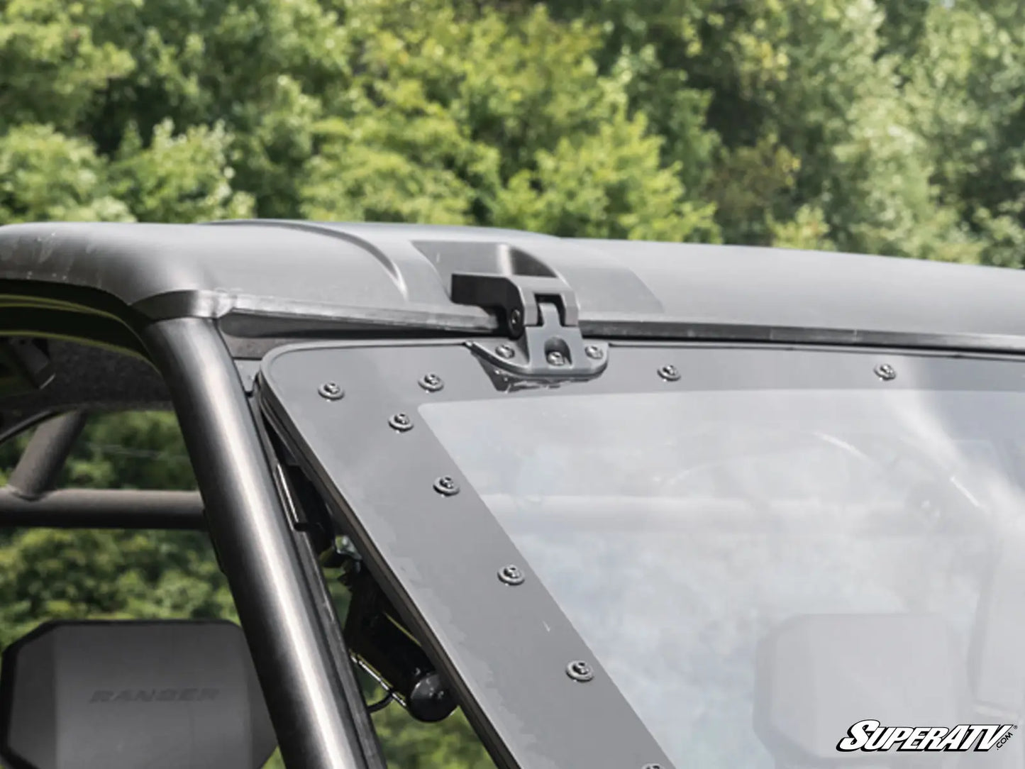 Close-up of a vehicle roof rack system with SuperATV branding against a blurred green background.