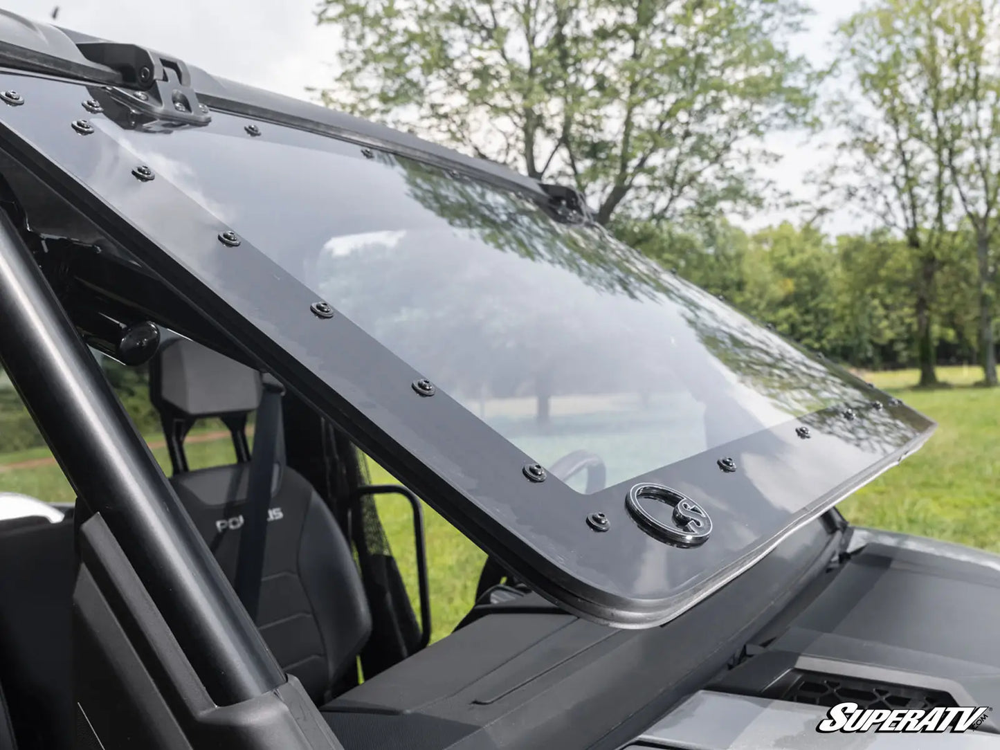 Black windshield of a vehicle with SuperATV branding, set against a natural background.