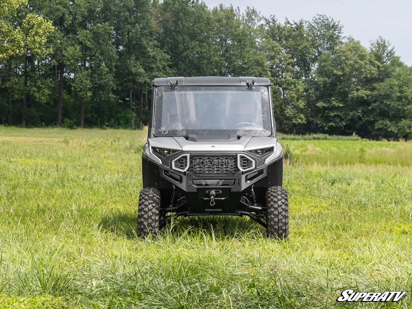 Utility vehicle in a grassy field with trees in the background