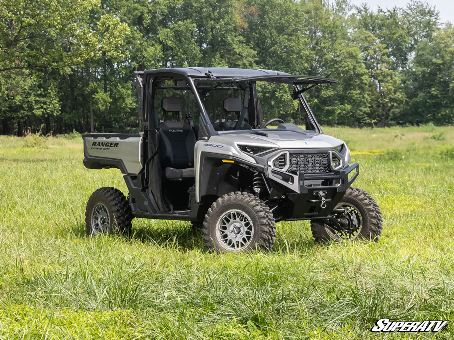 SuperATV Ranger vehicle in a grassy field with trees in the background