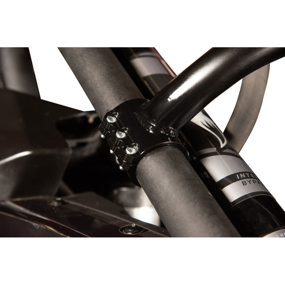 Close-up of a black metal bicycle handlebar clamp securing a black handlebar to a dark frame, with part of a silver and black tube visible.