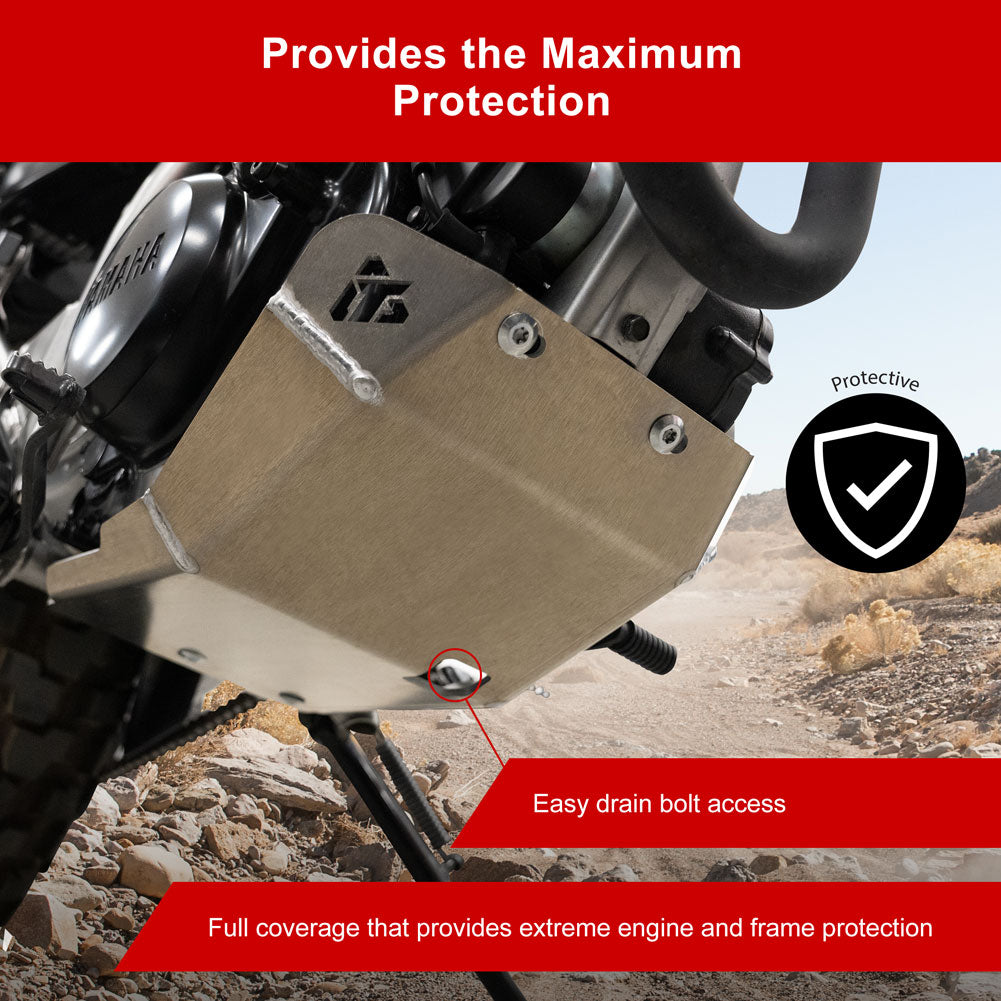 A brushed metal engine guard cover installed on a motorcycle, shown outdoors on a rocky desert road. The graphic includes text overlays reading 'Provides the Maximum Protection', 'Easy drain bolt access', and 'Full coverage that provides extreme engine and frame protection', along with a black shield icon with a white checkmark.