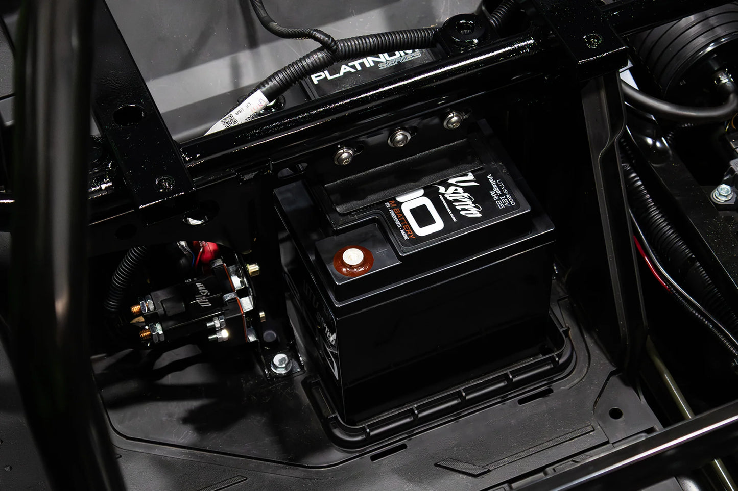 Close-up of a battery in a vehicle's engine compartment with visible branding.
