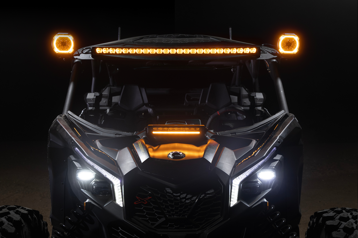 Front view of a BRP off-road vehicle with illuminated amber roof lights and white LED headlights