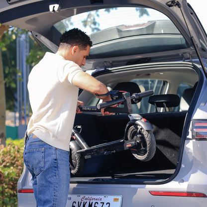 Man loading a scooter into the trunk of a car