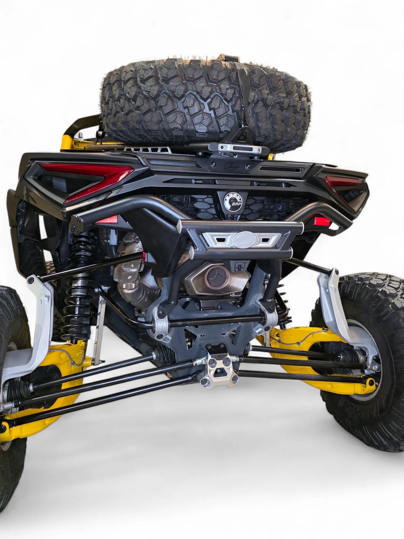 Close-up of a yellow and black off-road vehicle chassis with a spare tire on a white background