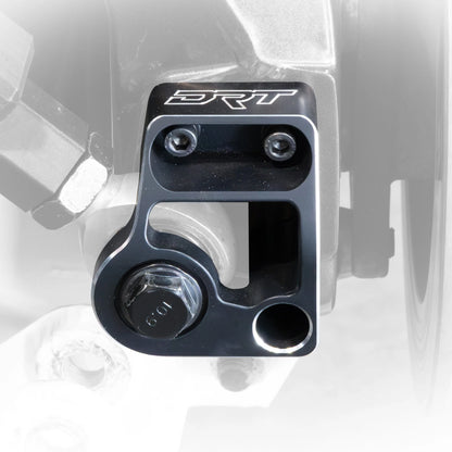 Black metal component with 'DRT' branding on a vehicle wheel assembly.